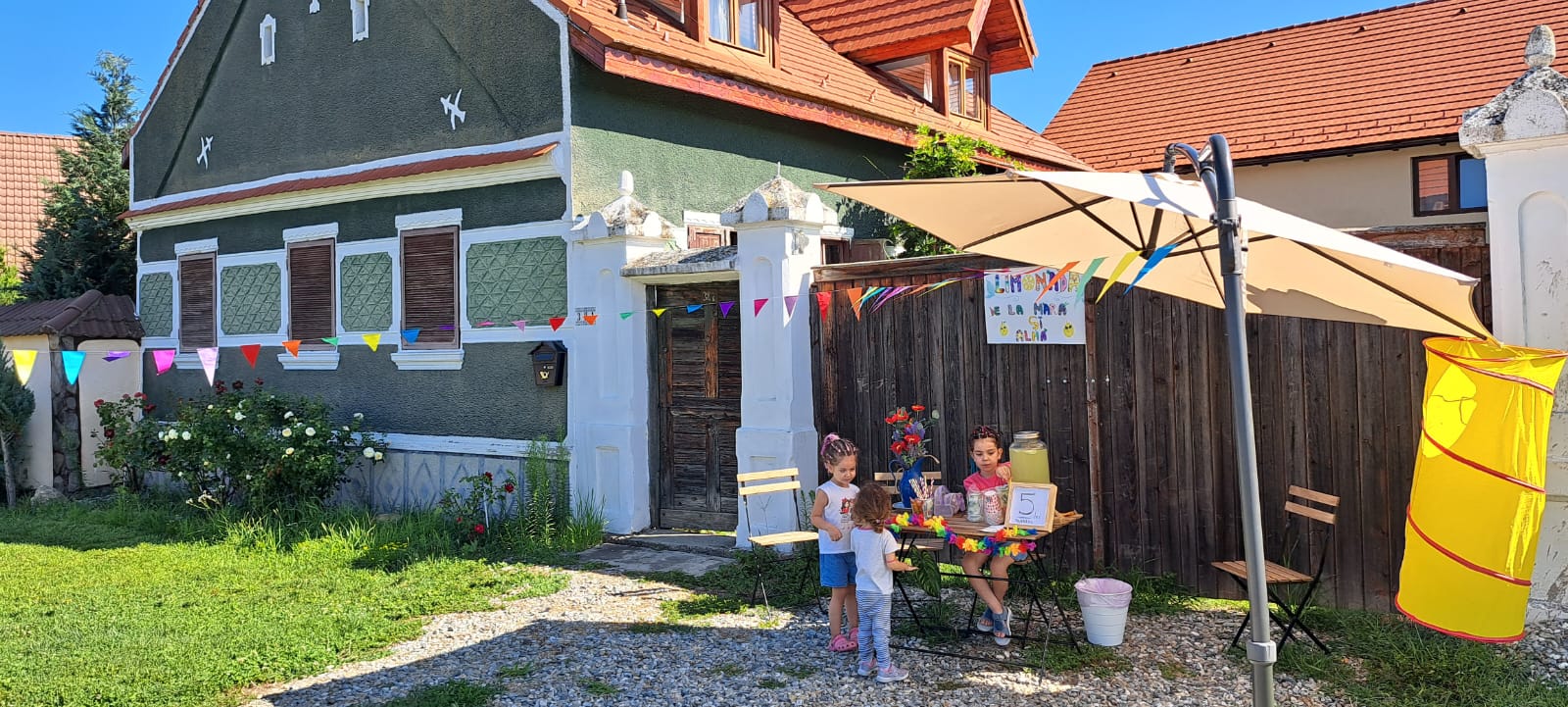 Porumbacu 381 – Curtea casei noastre, cu copii la joacă și familia relaxată la umbră