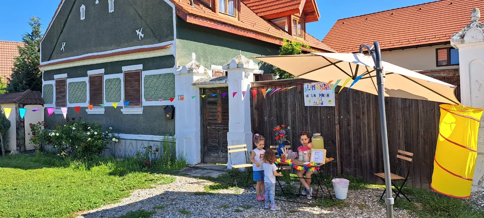 Porumbacu 381 – Curtea casei noastre, cu copii la joacă și familia relaxată la umbră